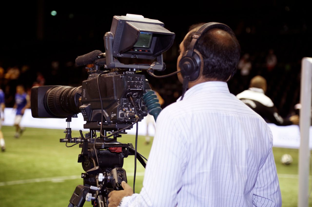 about-us A cameraman filming a soccer match in a stadium, capturing the action on video.